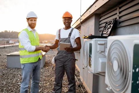 Men shaking hands and standing near air conditioner outdoors Stock Photos