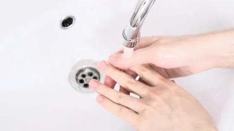The men in the sink washes his hands with soap. The water jet washes away the Stock Footage 156029688
