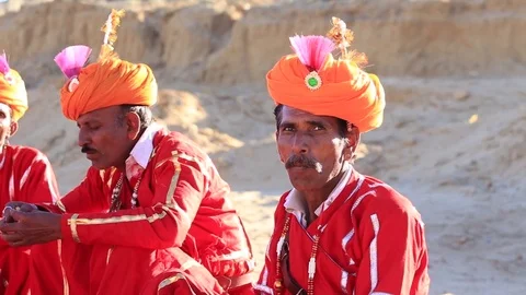 Men sit in desert and prepare for dancing in Desert Festival.  Jaisalmer, India Stock Footage 76763986