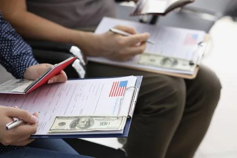 Men sit in line and filling visa application forms to get access to enter Stock Photos