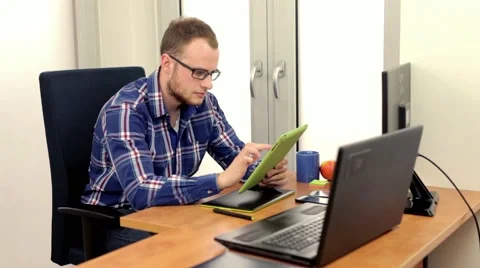 Men, siting behing his desk and alternately using tablet and smartphone, 스톡 동영상 49058349