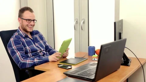 Men, siting behing his desk and alternately using tablet and smartphone, Stock Footage 49058429