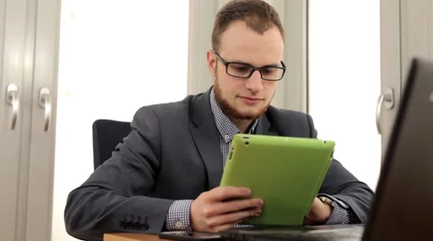 Men sitting behind the desk  he is  using tablet and computer Stock Footage 49337793