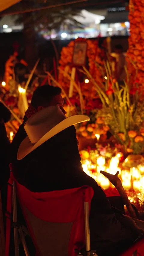 Men sitting by glowing marigold altar at Michoacan night vigil. Stock Footage 344886756