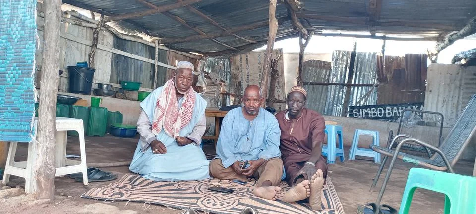 Men Sitting Inside a Makeshift Community Shelter Stock Photos