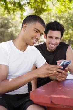Men Sitting at Picnic Table, Looking at Cellular Phone Stock Photos