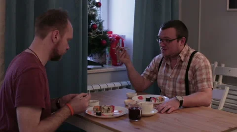 Men sitting at table eating sushi with chopsticks Stock Footage 58799860