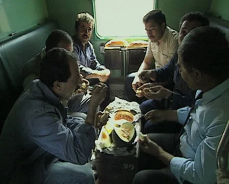 Men sitting in train carriage eating together Stock Footage