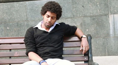 A men sleeping on the bench and then waking up. Stock Footage 54176514