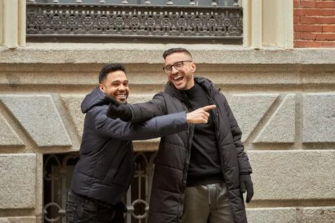 Men smiling and pointing different directions while standing outdoors on the Foto stock