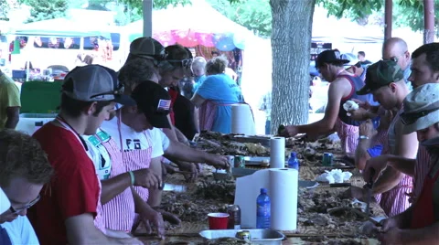 Men socialize while preparing meat for sandwiches for small town summer festival Stock Footage 40853708