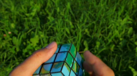 Men solves rubik's cube on green grass background Video stock 518848