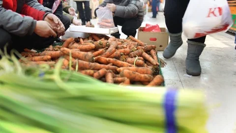 Men sorting through fresh carrots in a Chinese fruit and vegetable market, China 스톡 동영상 84696576