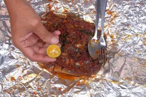 Men squeeze the lime while eating roasted stingrays with hot spicy in aluminu Stock Photos