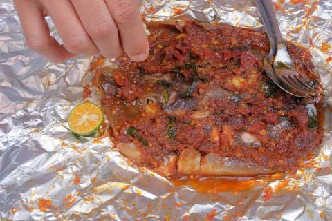 Men squeeze the lime while eating roasted stingrays with hot spicy in aluminu Stock Photos