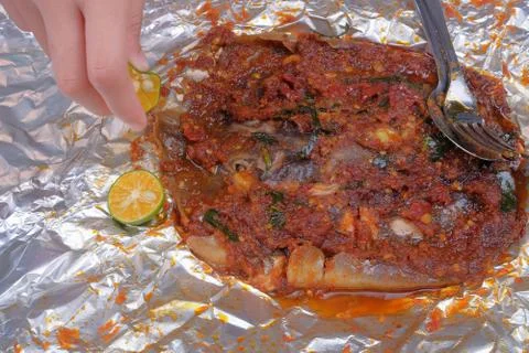 Men squeeze the lime while eating roasted stingrays with hot spicy in aluminu Stock Photos