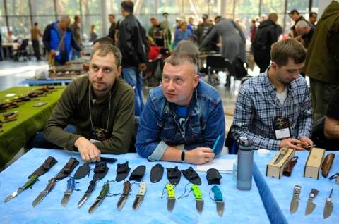 Men standing in front of a table with handmade knives and talking to a sales Stock Photos