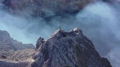 A men stands on the top of a mountain or volcano 4k drone. eruption. crater Stock Footage 136059839