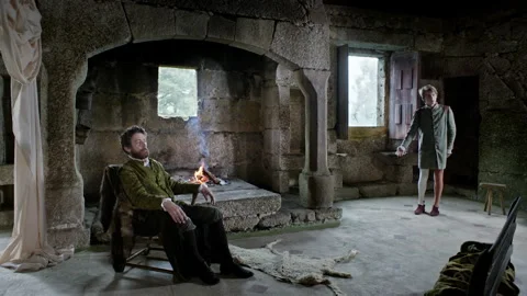 Men in a stone room talk about an important matter near a fire Stock Footage 327963564