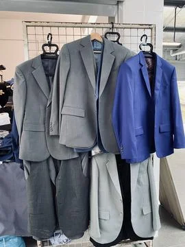 Men suits jacket hanging on the rack factory tailor Stock Photos