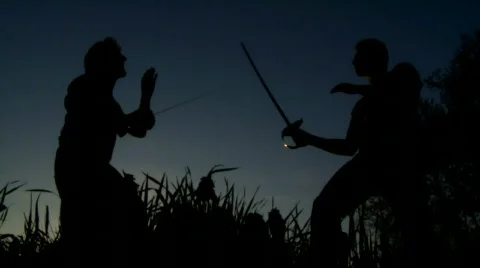 Men at sunset fighting with swords 動画素材 496501