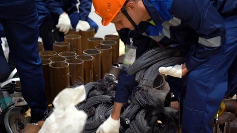 Men take material for work. Piles of cut, bound metal wire lie on floor.  Stock Footage 126355486