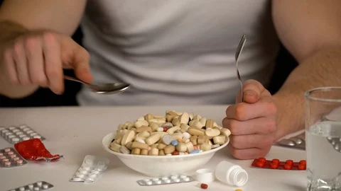 Men taking spoon to eat tablets from bowl, pharmaceutical products Stock Footage 123108531