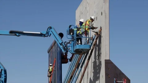 Men in a telehandler and ladder working in The Trump's Wall Stock Footage 99043893