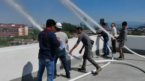 Men Testing Fire Hose Reels with High Pressure Water Spray Stock Footage 338427047