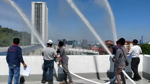 Men Testing Fire Hose Reels with High Pressure Water Spray Stock Footage 338427098