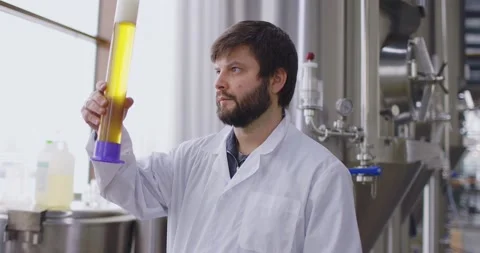 Men testing quality of fresh beer in a brewery. Brewer dressed in lab coat Video stock 148231154