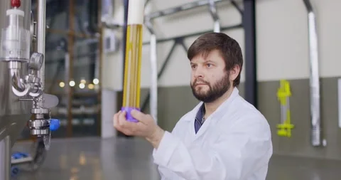 Men testing quality of fresh beer in a brewery. Brewer dressed in lab coat Video stock 148231311