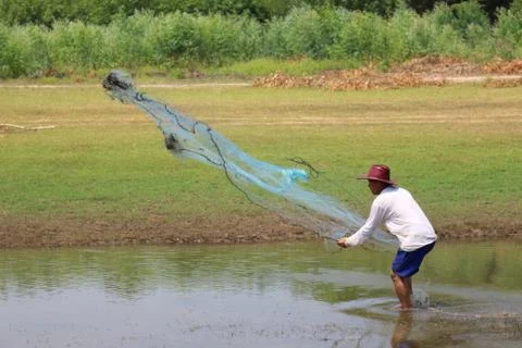 Men throw a net on the river. Stock Photos