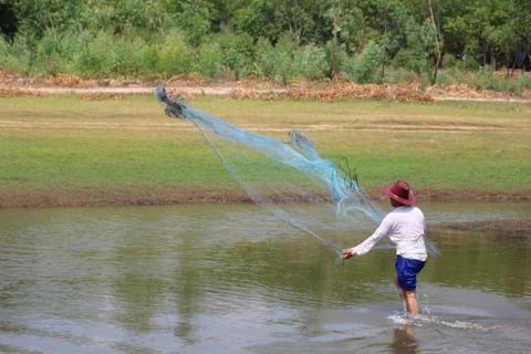 Men throw a net on the river. Stock Photos