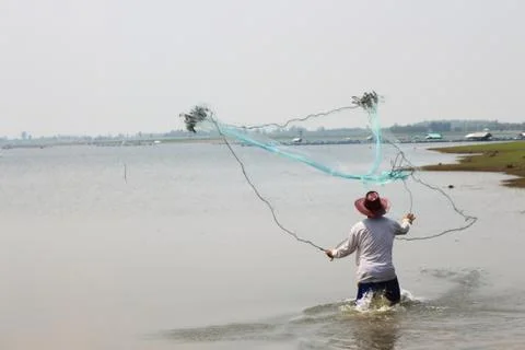 Men throw a net on the river. Stock Photos