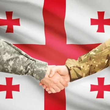 Men in uniform shaking hands with flag on background - Georgia Фото