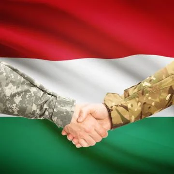 Men in uniform shaking hands with flag on background - Hungary 스톡 사진