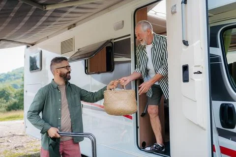 Men unloading camper van at start of autumn weekend getaway. Stock Photos