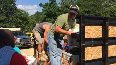 Men unloading supplies from flatbed for flood victims (HD) Stock Footage 64589135