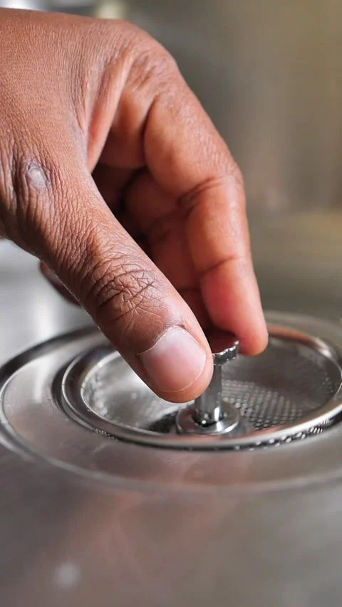 Men utilize their hands to carefully position the drain cover inside the sink at Stock Footage 345621565