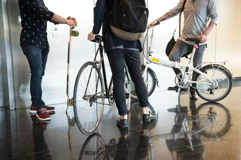 Men waiting for elevator with bicycles and longboard, low section Fotos de archivo