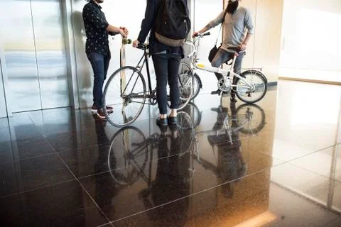 Men waiting for elevator with bicycles and longboard, low section Fotos de archivo