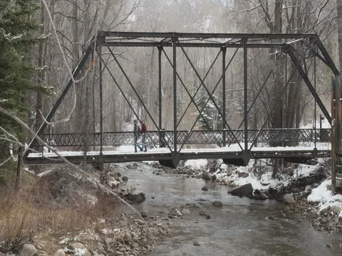 Men walking on footbridge over river during winter Stock Footage 84504007