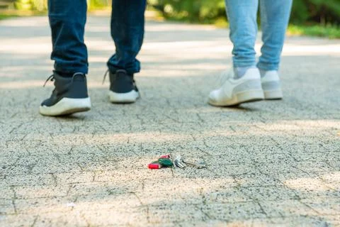 Men walking outside, focus on lost keys Stock Photos