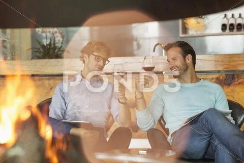 Men wine tasting at fireplace in winery tasting room Stock Photos