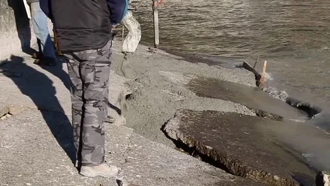 Men at work on lake river with cement vs water and waves Stock Footage 73450266