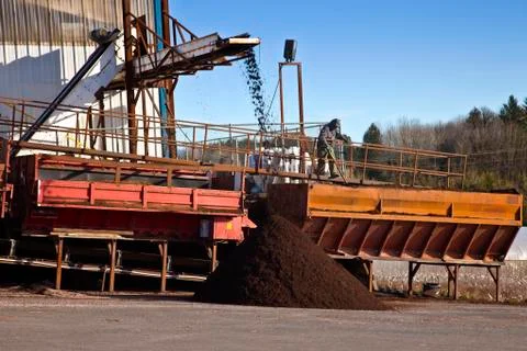 Men at work processing compost for agriculture. Stock Photos