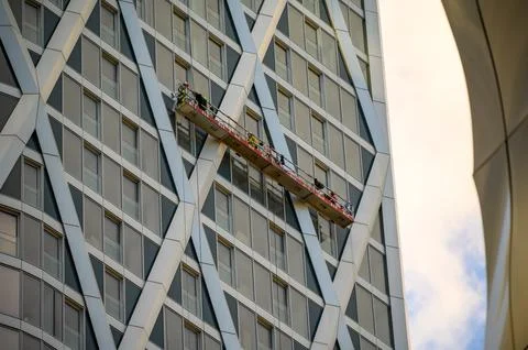 Men work from suspended platform on skyscraper Stock Photos