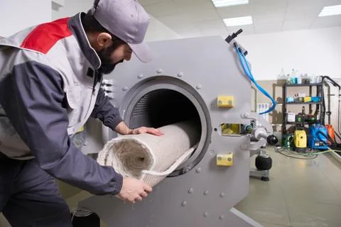 Men workers get carpet from an automatic washing machine and put in in dryer in Foto stock