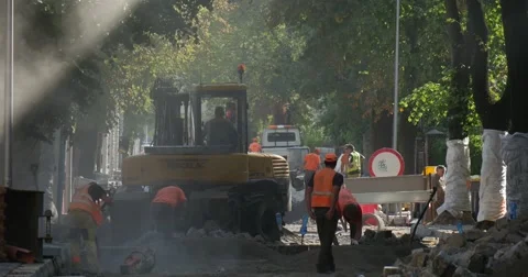 Men Workers In Yellow Workwear at The Sity Street are Digging Yellow Excavator Stock Footage 54336543
